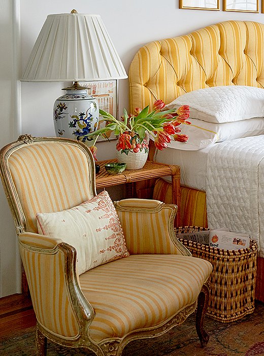 Striped upholstery, ornately carved wood, a chinoiserie lamp, and fresh flowers make this room fit for a Prince Regent, but the wicker basket and restful white bedding keep it from looking dated. Photo by Tony Vu.
 

